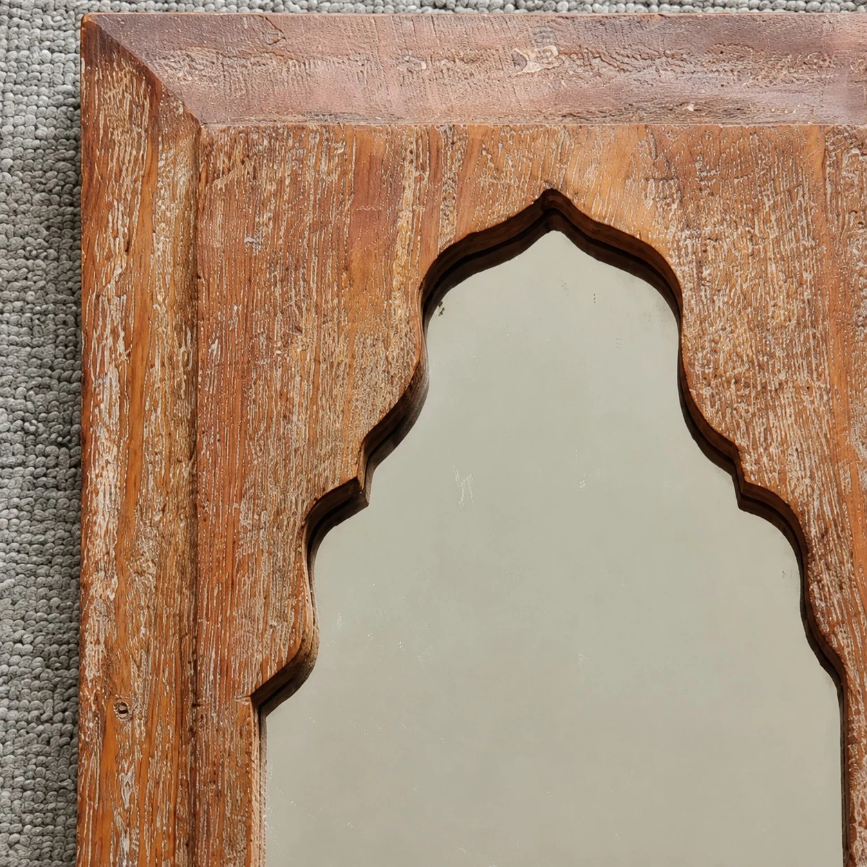Close view of carved arch detail on the wooden mirror frame