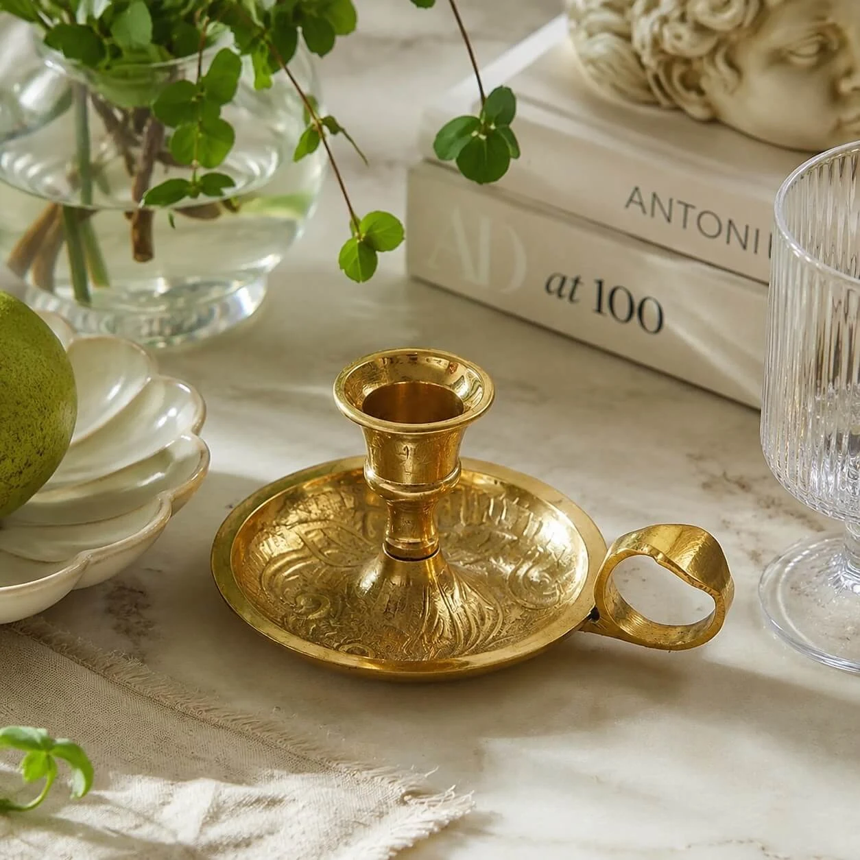 Brass candlestick styled beside books and greenery