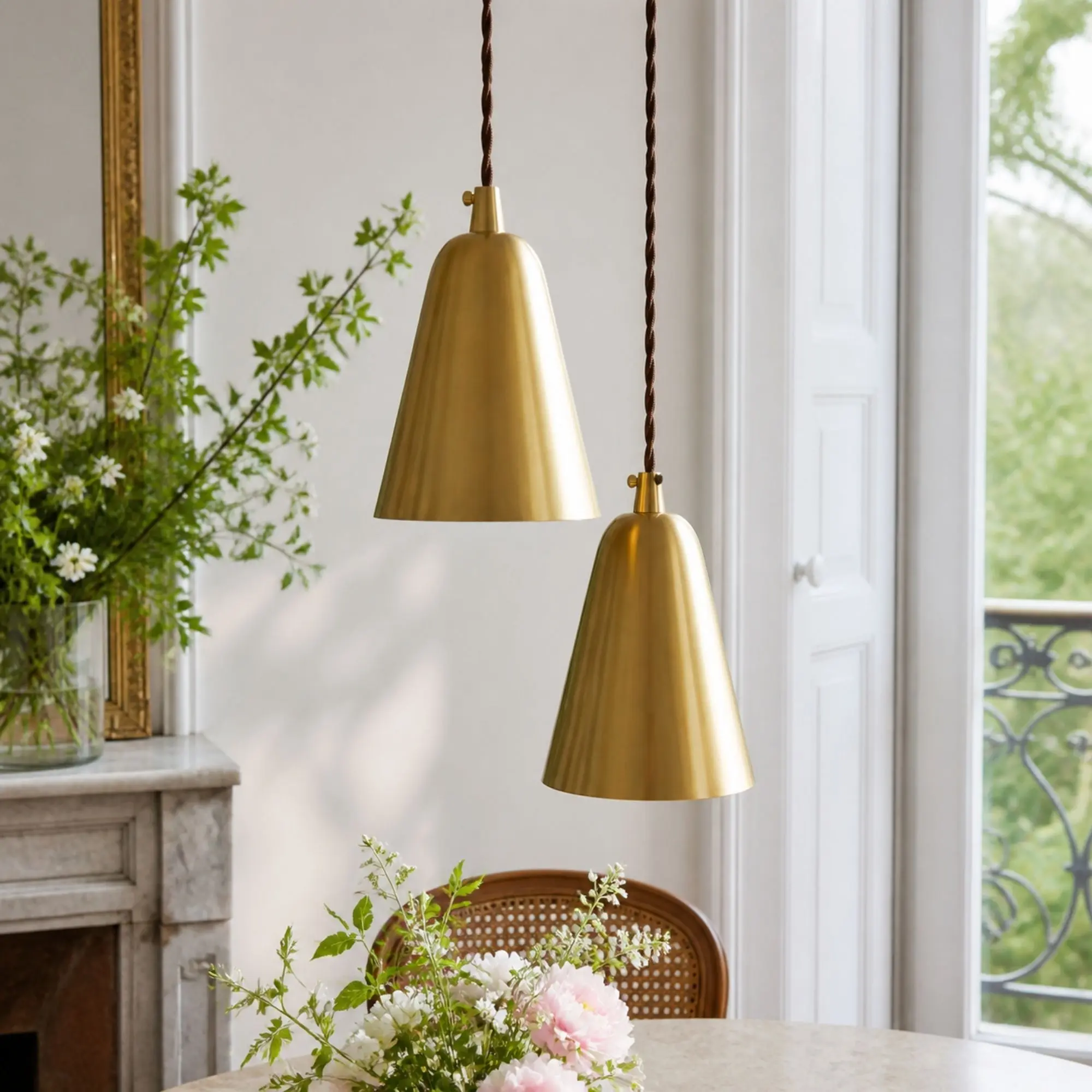 Pair of straight natural brass pendant lights by a window