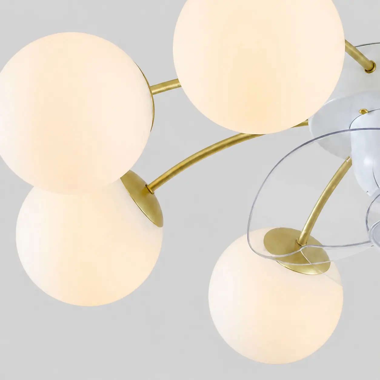Close-up of white glass globes and gold-toned arms