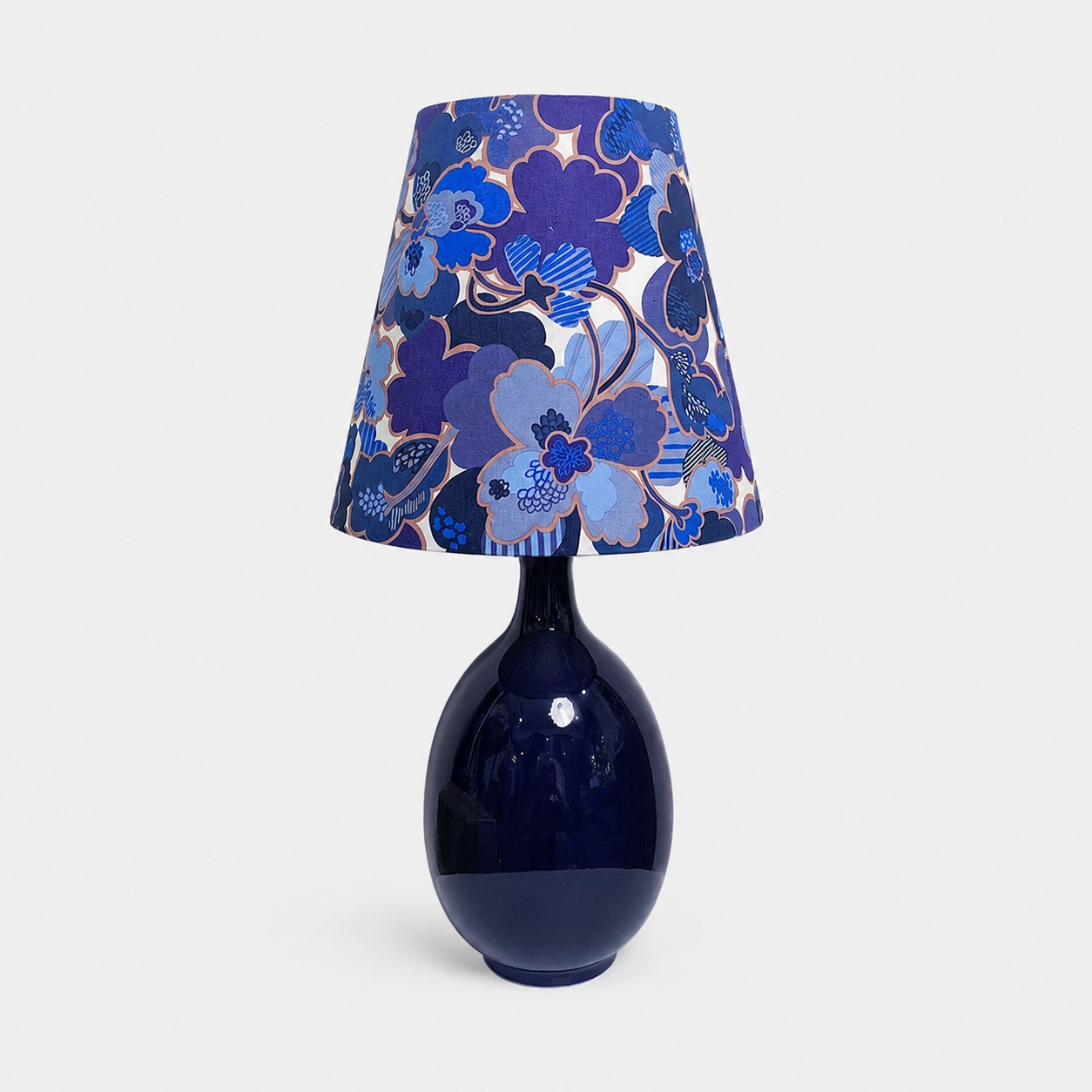 Blue floral fabric ceramic table lamp on plain background