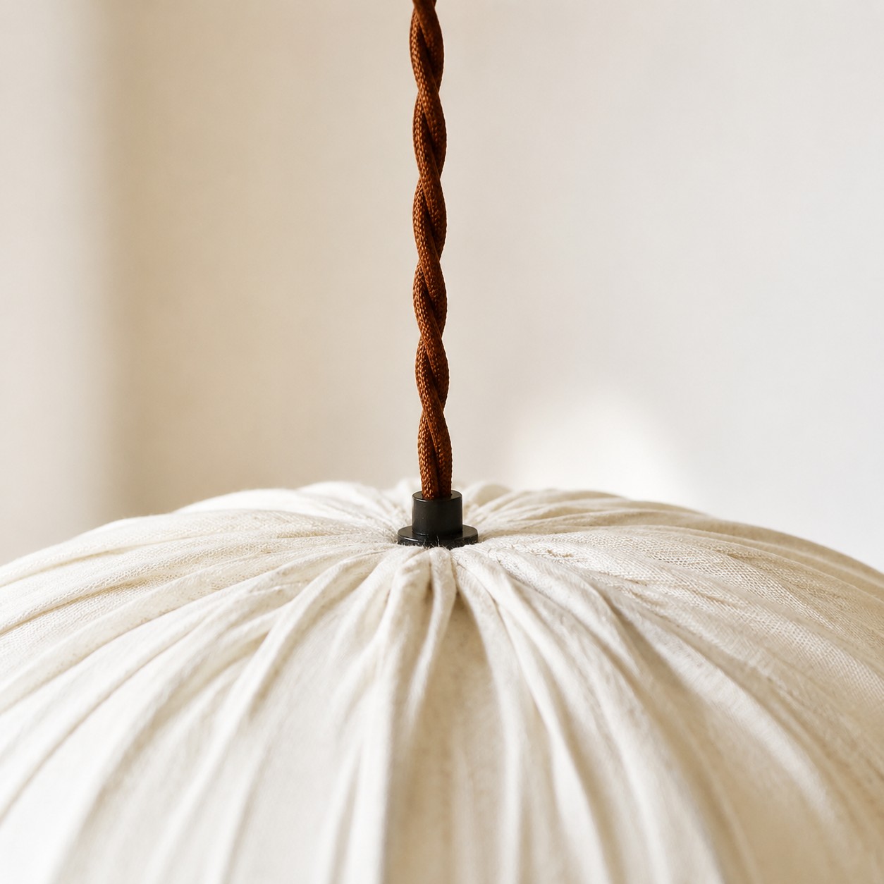 Close view of twisted hanging cord and oatmeal fabric shade top
