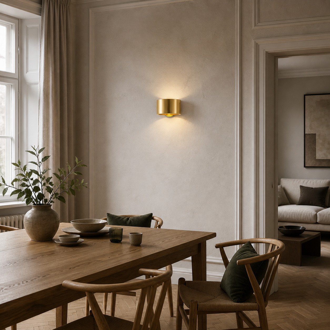 Aplique de parede cilíndrico em latão dourado em um ambiente interno.